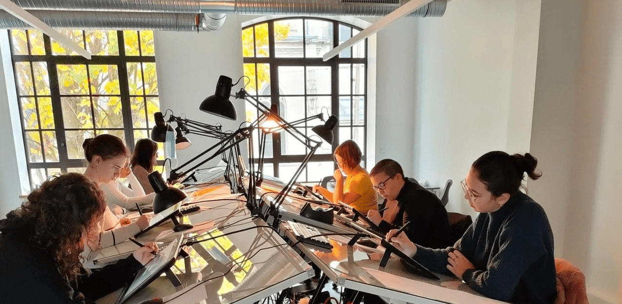 Des étudiants de Lanimea dessinent à leur table lumineuse, dans une salle aux grandes fenêtres